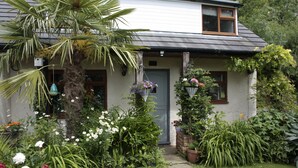 A house with a front door, a small porch, and a garden with various plants and flowers.
