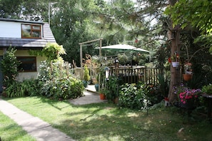 A garden with a wooden pergola, potted plants, and a pathway leading to a house. - Pond View Cottage with beautiful views - Dog friendly (cosy and tranquil) (North Thoresby)