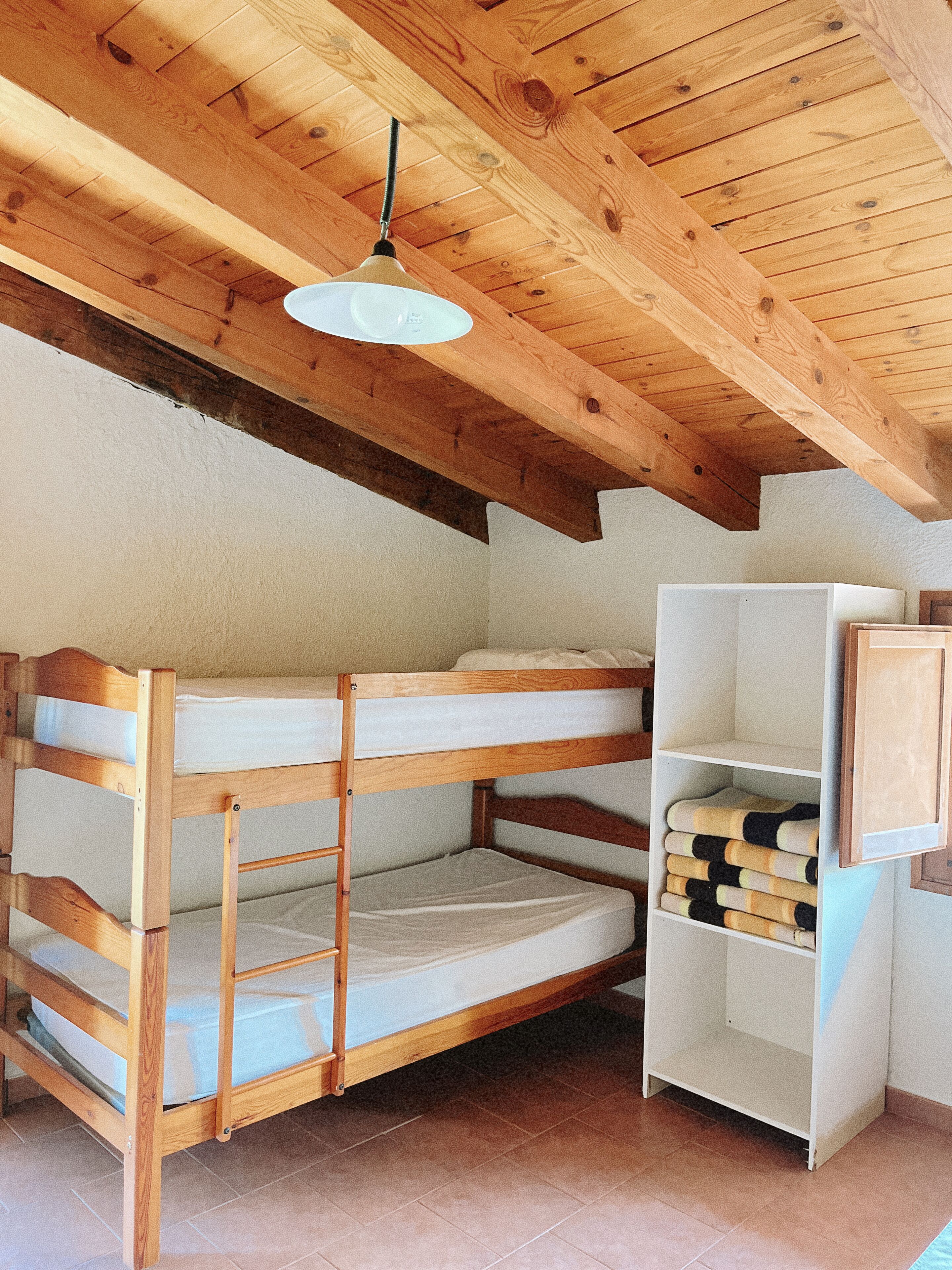 A bunk bed with a wooden headboard and a white shelf unit beside it.
