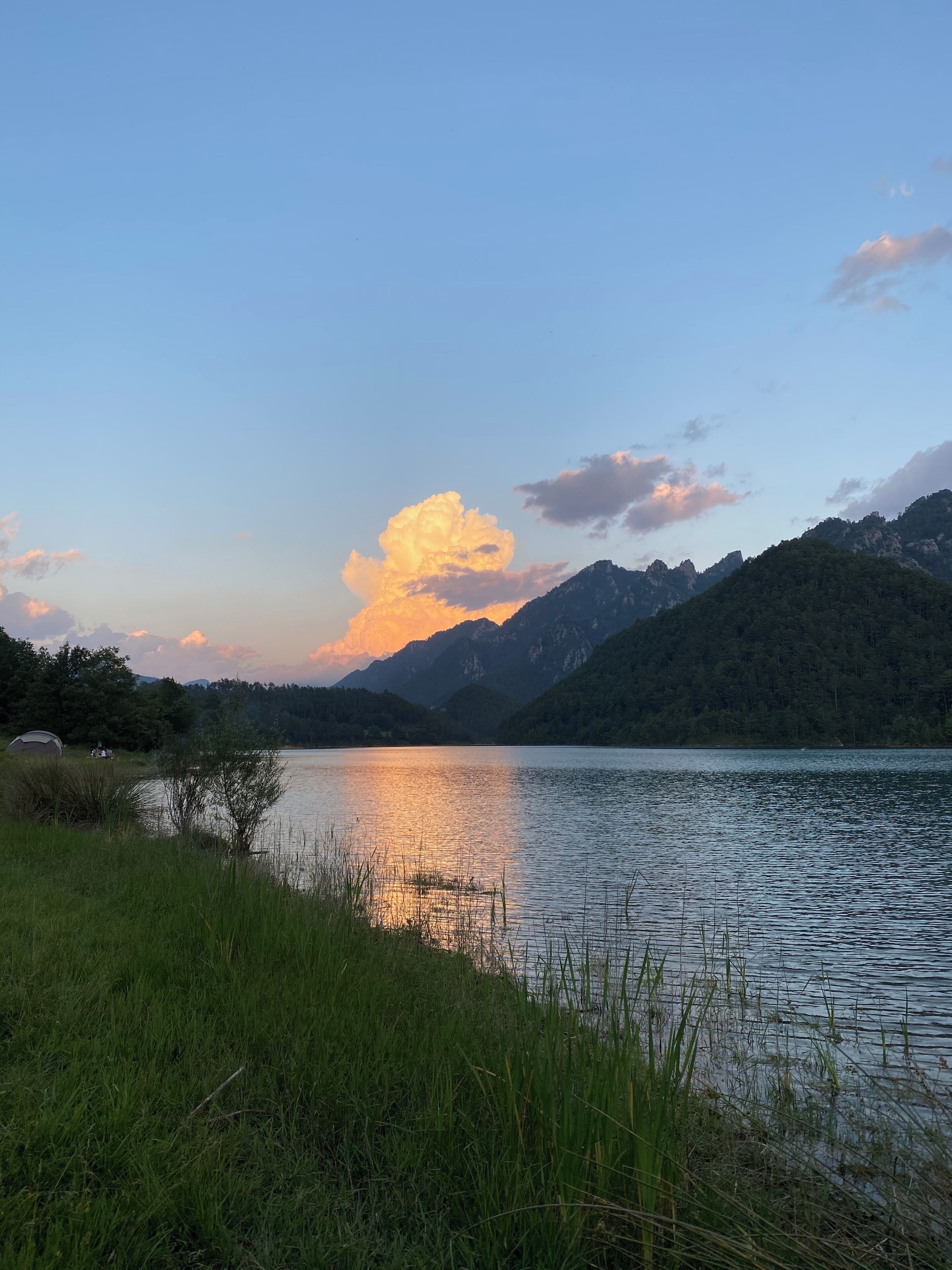 Un lago tranquilo con montañas al fondo y un cielo despejado.