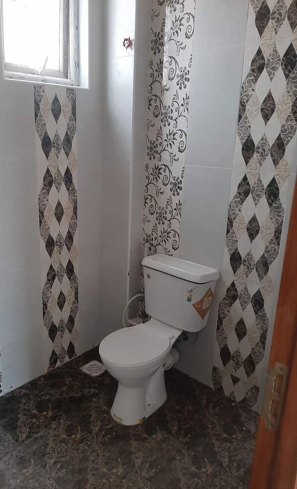 Een kleine badkamer met toilet, douche en raam.