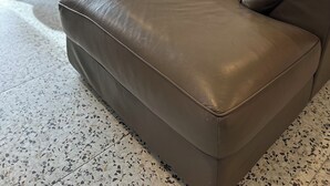 Un salon moderne avec un canapé en cuir marron, une table basse ronde et un divan gris agrémenté de coussins.