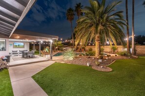 Un giardino sul retro con piscina, palme e mobili da esterno.