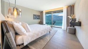 A modern bedroom with a large bed, a view of mountains through a sliding door, and a pendant light above the bed.