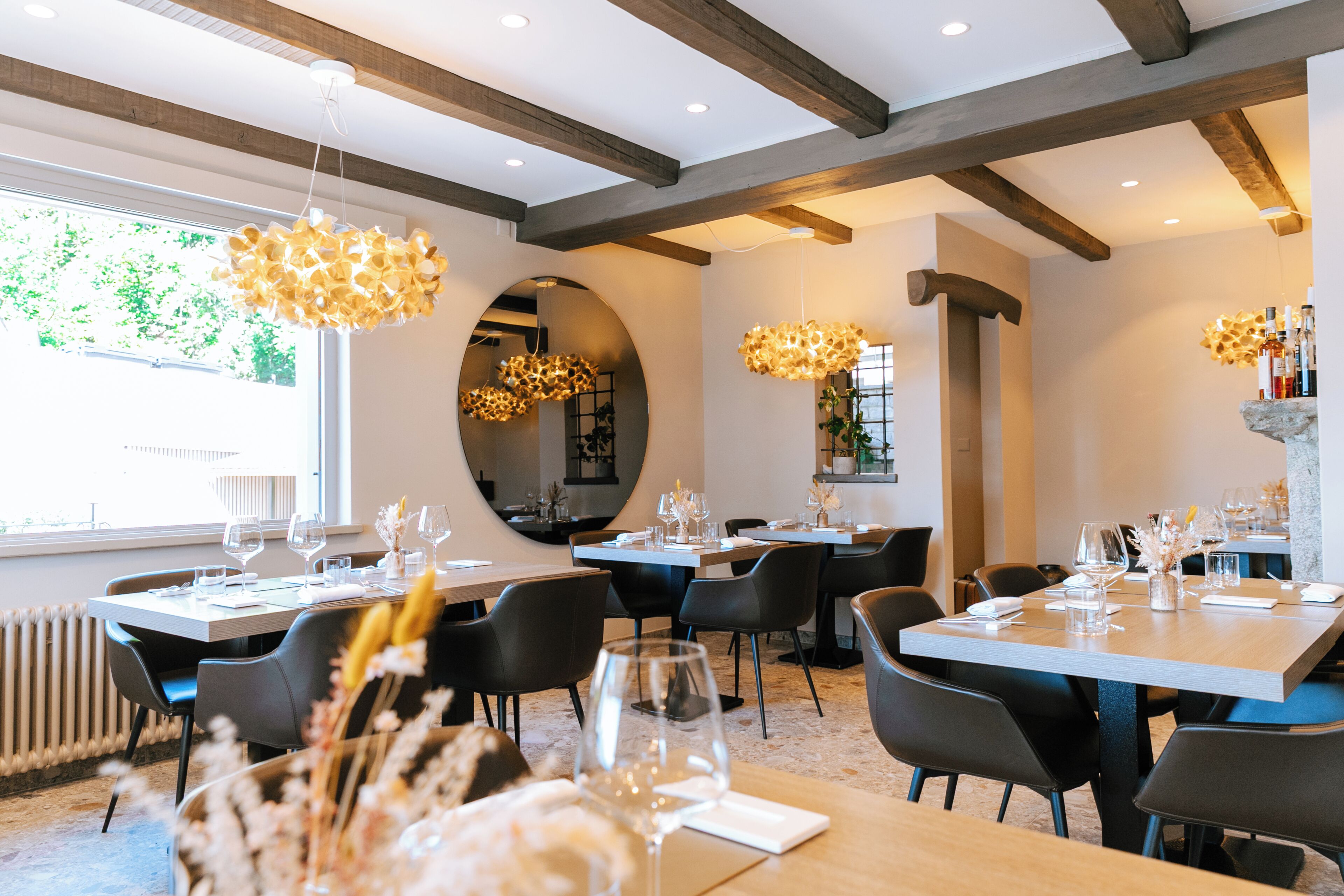 A restaurant with multiple dining tables, chairs, and hanging light fixtures.