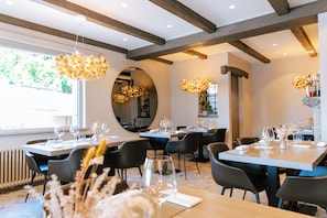 A restaurant with multiple dining tables, chairs, and hanging light fixtures. - Boutique Hotel Elisabetta (Ronco sopra Ascona)