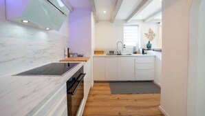 A modern kitchen with white cabinetry, a marble countertop, and a built-in oven.