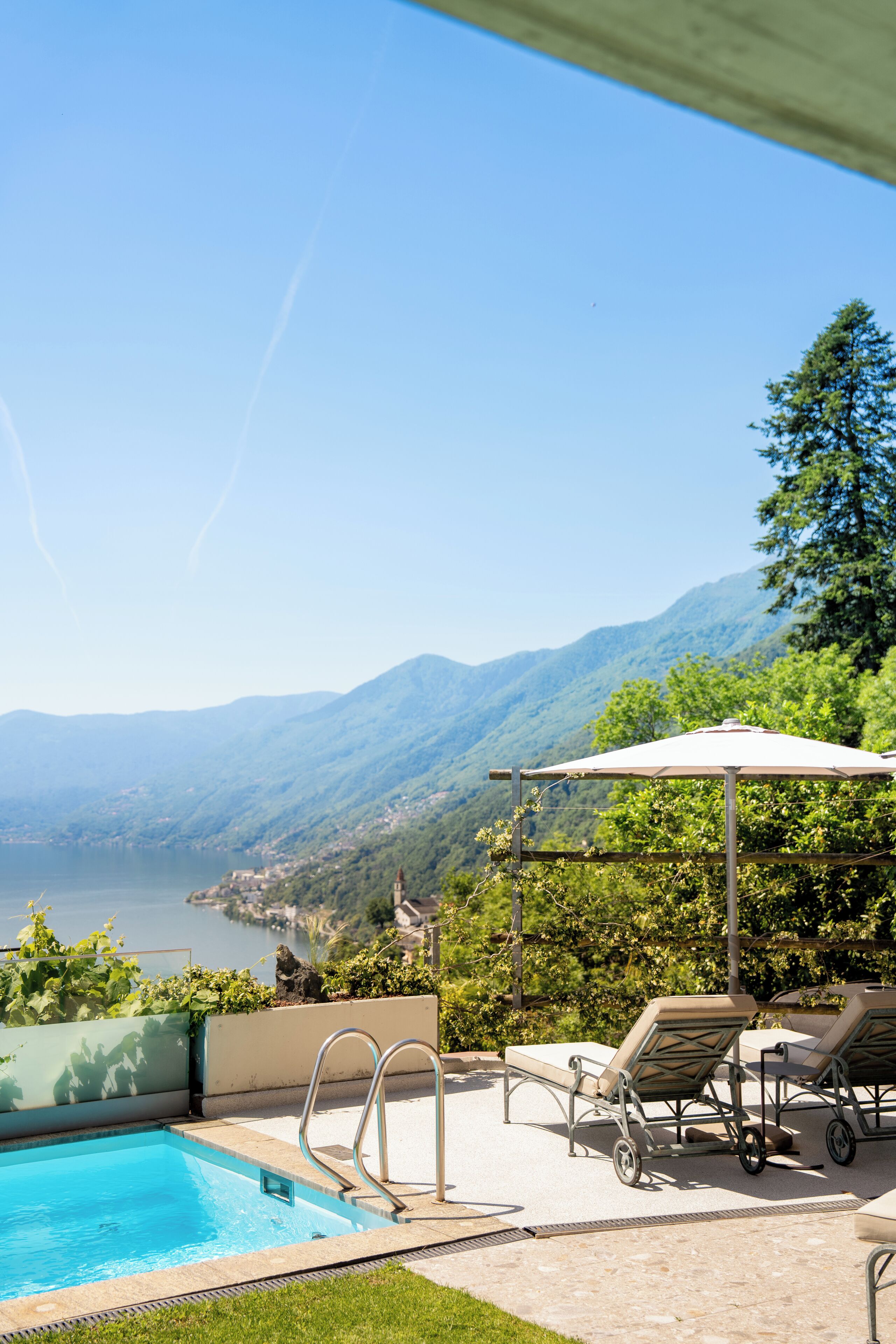 Une piscine dotée de chaises longues et d’une pergola, offrant une vue sur un paysage montagneux.