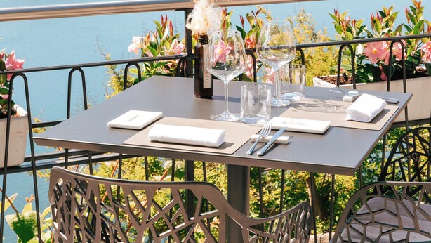 A dining table set with a view of a lake and mountains.
