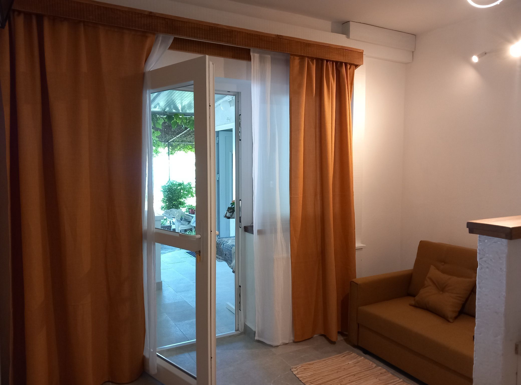 A room with a sliding glass door leading to an outdoor area, a brown sofa, and a small table.