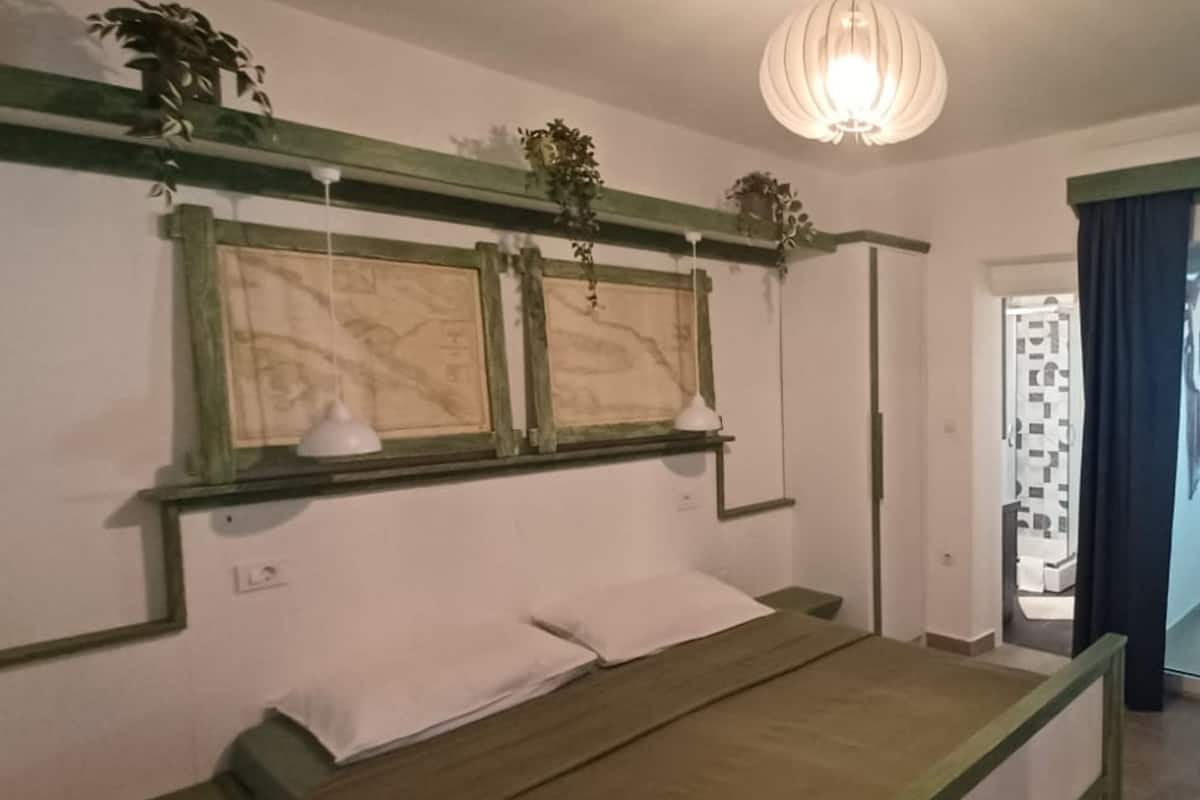 A bedroom with a bed, two wall-mounted lamps, and a hanging plant.