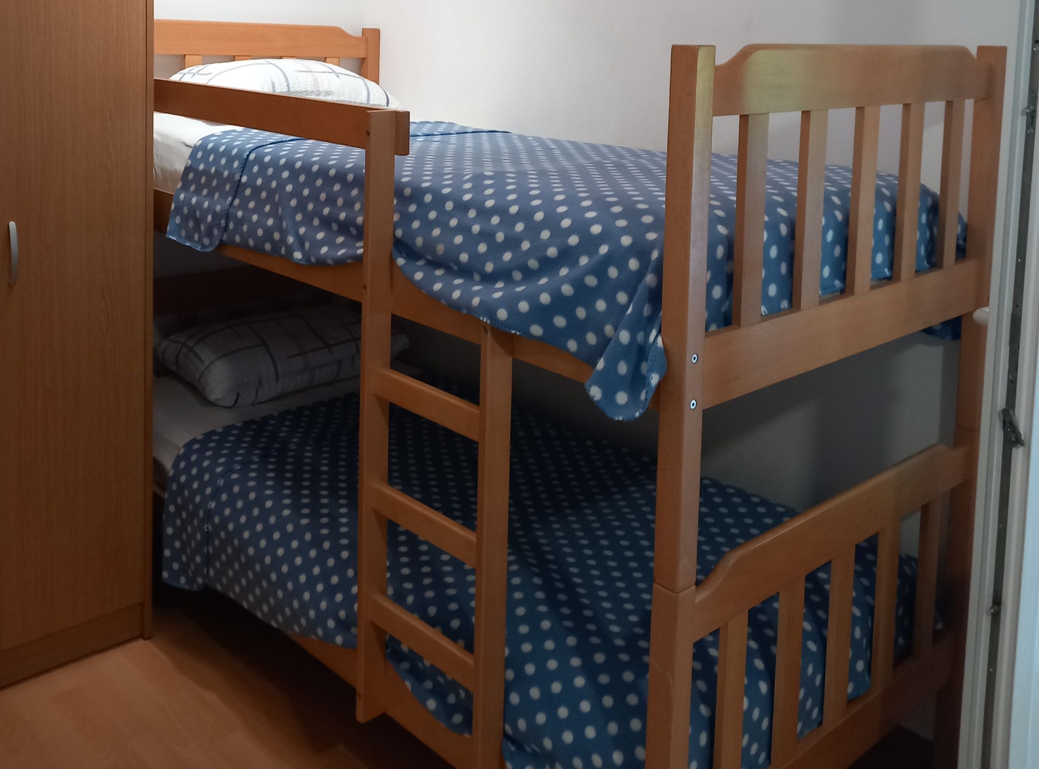 Un lit superposé avec une structure en bois et une literie bleue à pois blancs.