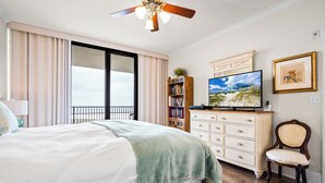 Ein Schlafzimmer mit einem Bett, einem Fernseher, einem Bücherregal, einer Kommode und einem Stuhl.