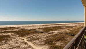 Ein Balkon mit Blick auf einen Strand und eine Bahnlinie.
