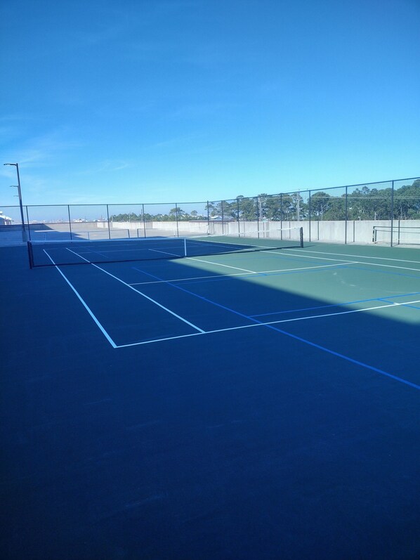 Un court de tennis en plein air, sous un ciel dégagé.