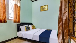 Una cama bien hecha con cabecera negra, ropa de cama blanca y una colcha azul y blanca a rayas.