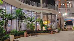 A hotel with a curved facade, large windows, and a balcony with railings. - PGC Chennai Resort & Club By SSS (Ponneri)