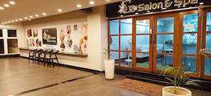 Un salón de belleza y spa con recepción, piso de madera y un amplio ventanal.