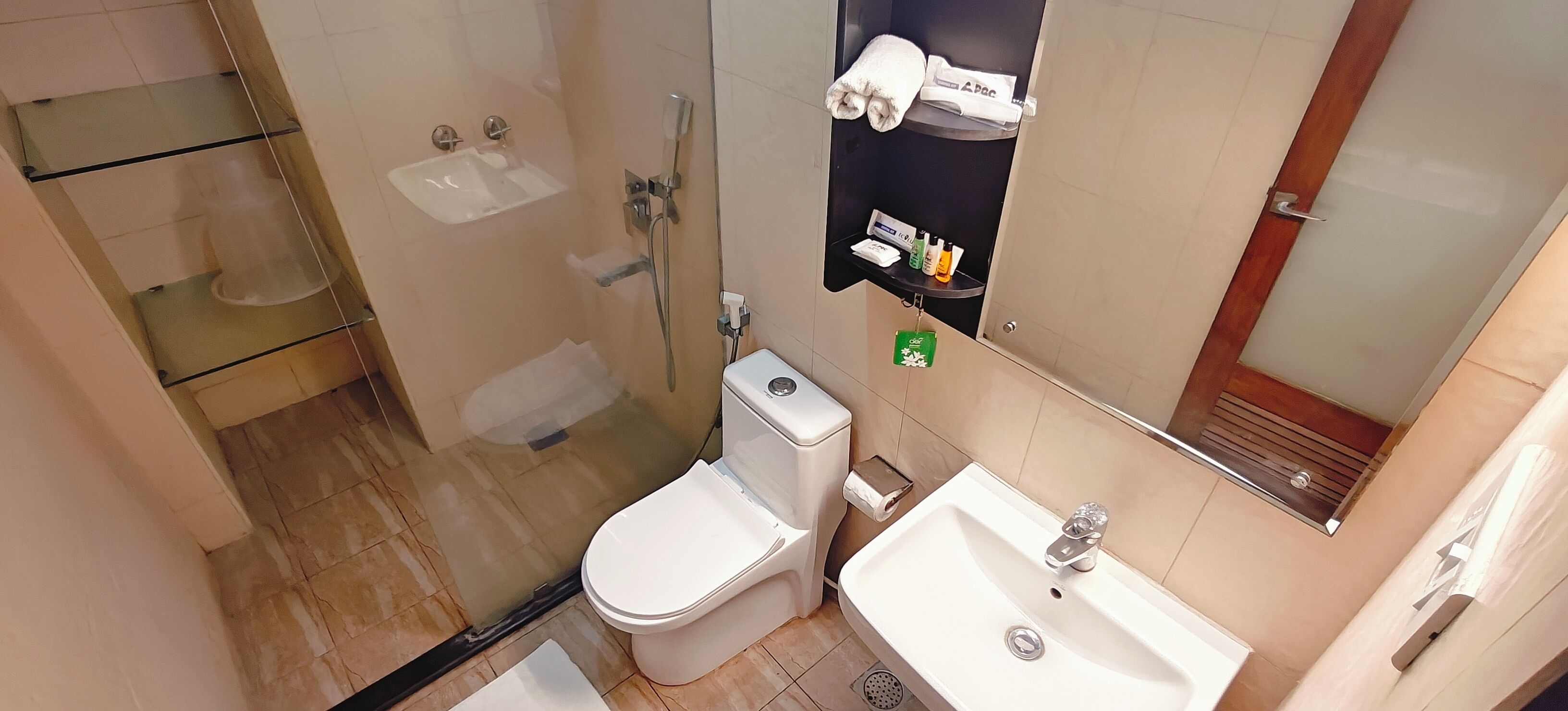 A bathroom with a glass-enclosed shower, a white toilet, a sink, and a towel rack with towels.