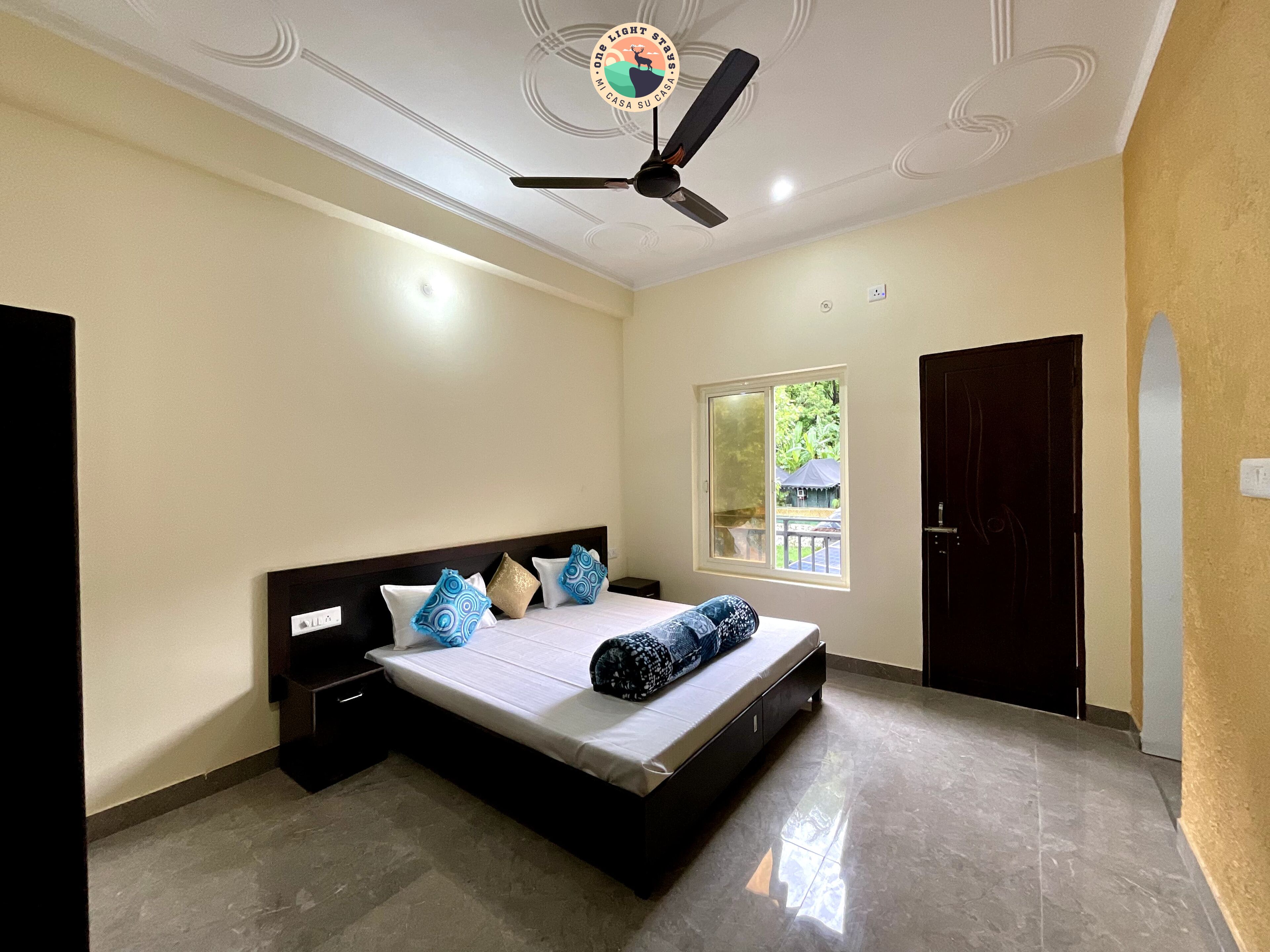 A bedroom with a bed, a ceiling fan, a window, and a door.