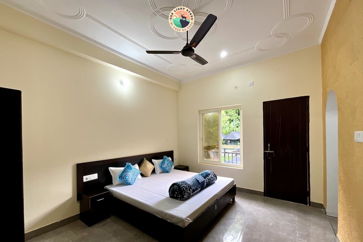 A bedroom with a bed, a ceiling fan, a window, and a door.