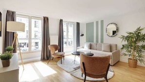 Un salon moderne avec un canapé, des fauteuils, une lampe et une plante en pot.