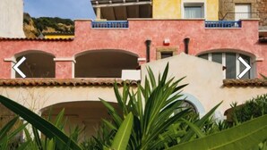 Ein Gebäude mit einer rosa Fassade, mehreren Bögen und einem Balkon mit blauen Geländern.