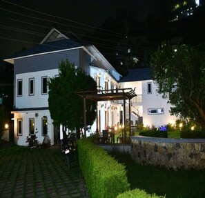 A two-story building with a covered outdoor seating area and a paved driveway.