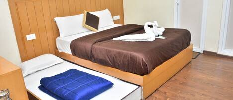 A hotel room with a bed, a blue blanket, a white towel, and a wooden headboard.