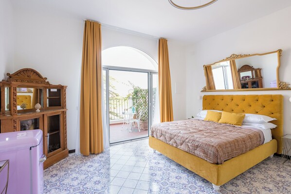 A bedroom with a bed, a dresser, a mirror, and a view to the outside. - Casa Enzina (Sorrento)