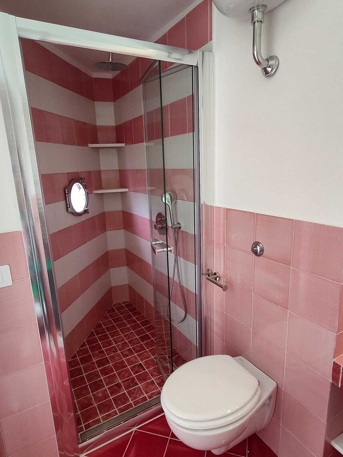 Un baño con ducha, inodoro y espejo.