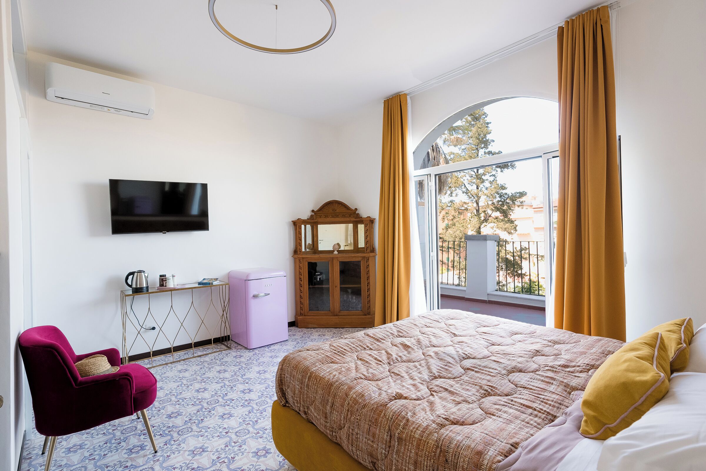 A bedroom with a bed, a TV, a desk, a chair, and a window with curtains.