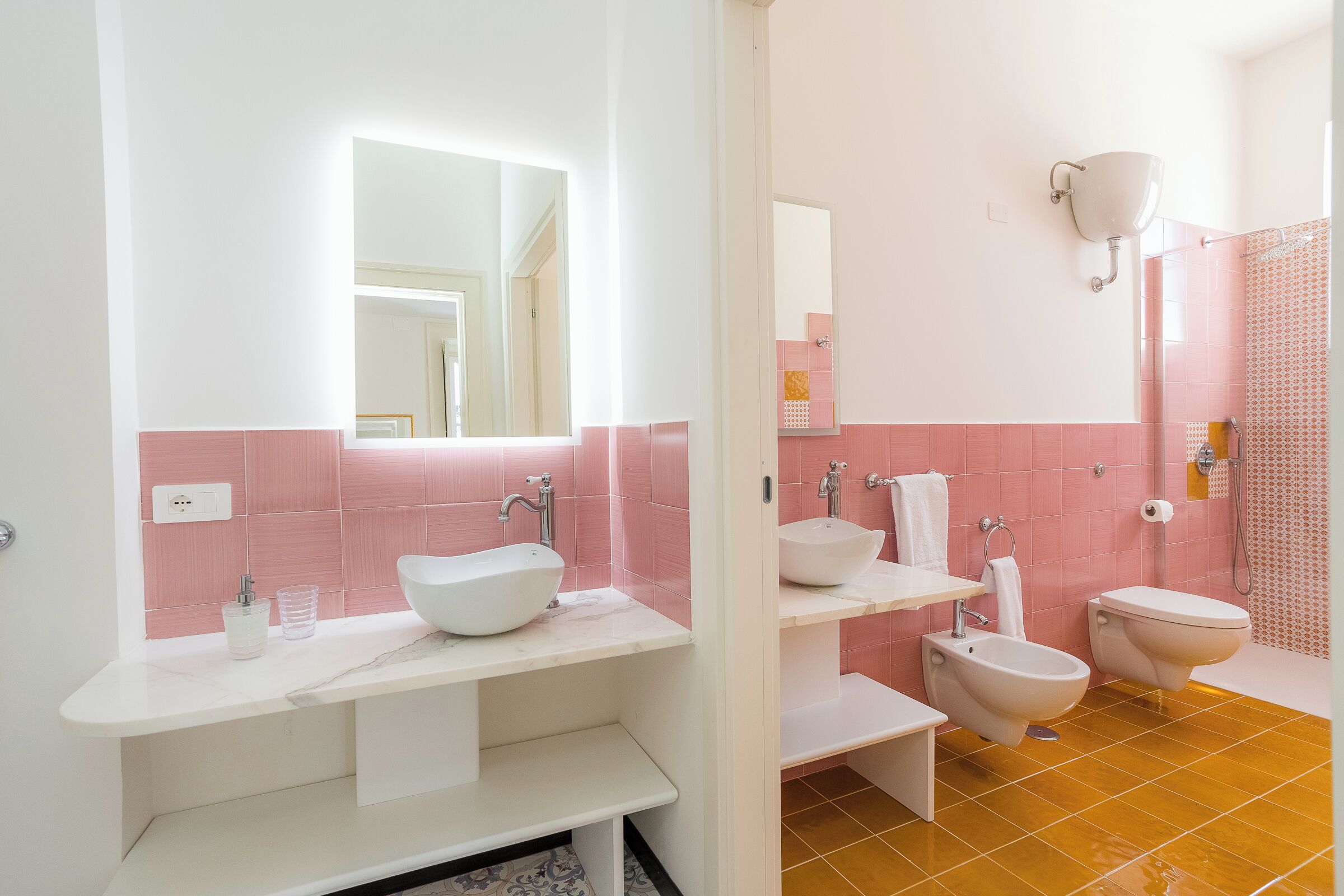 Un bagno con un lavandino bianco, uno specchio, un water e un bidet.