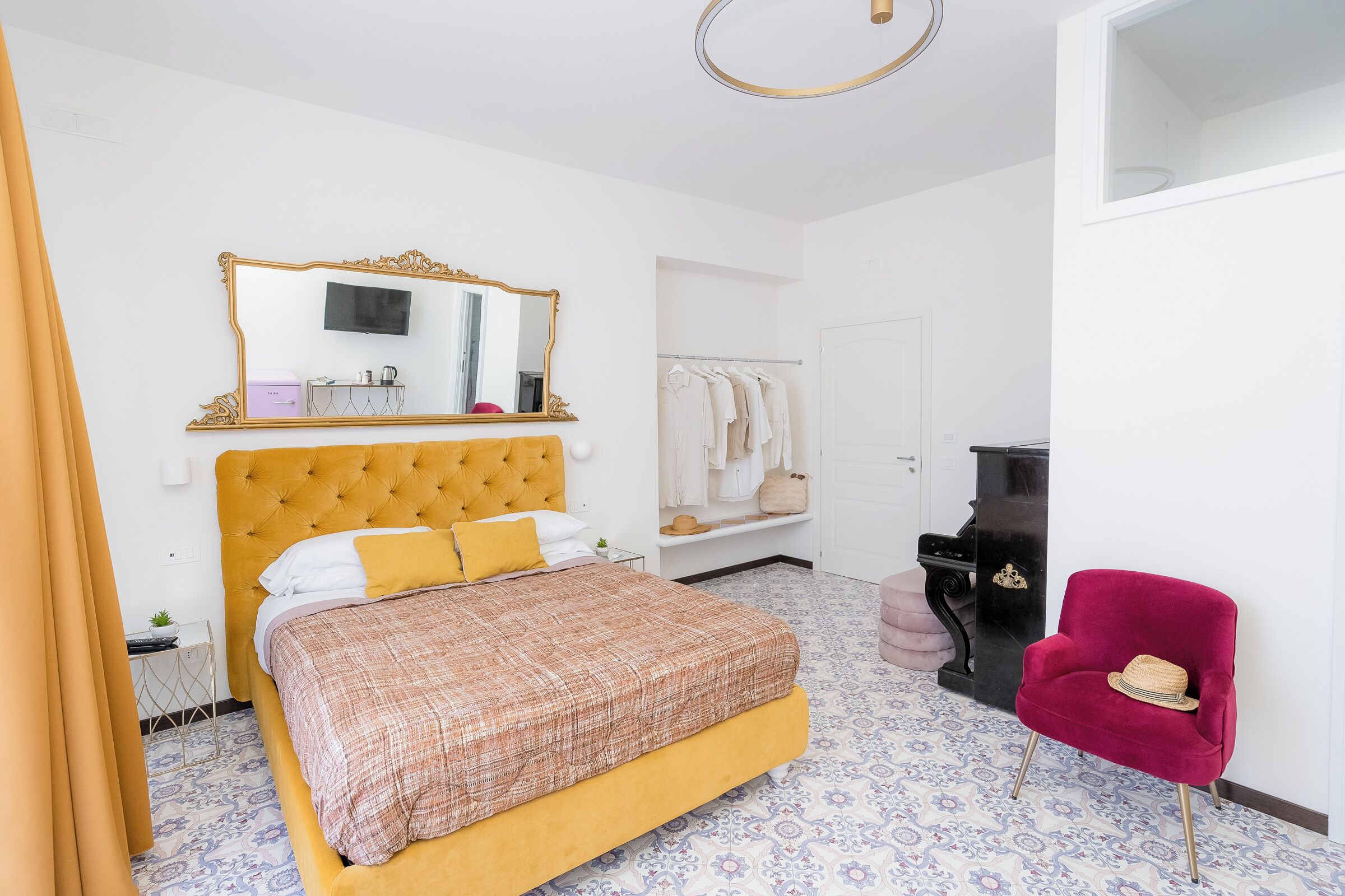 A bedroom with a bed, a vanity with a mirror, a wardrobe, a chair, and a television.