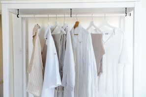 A white closet with multiple hangers holding various shirts and blouses. - Casa Enzina (Sorrento)