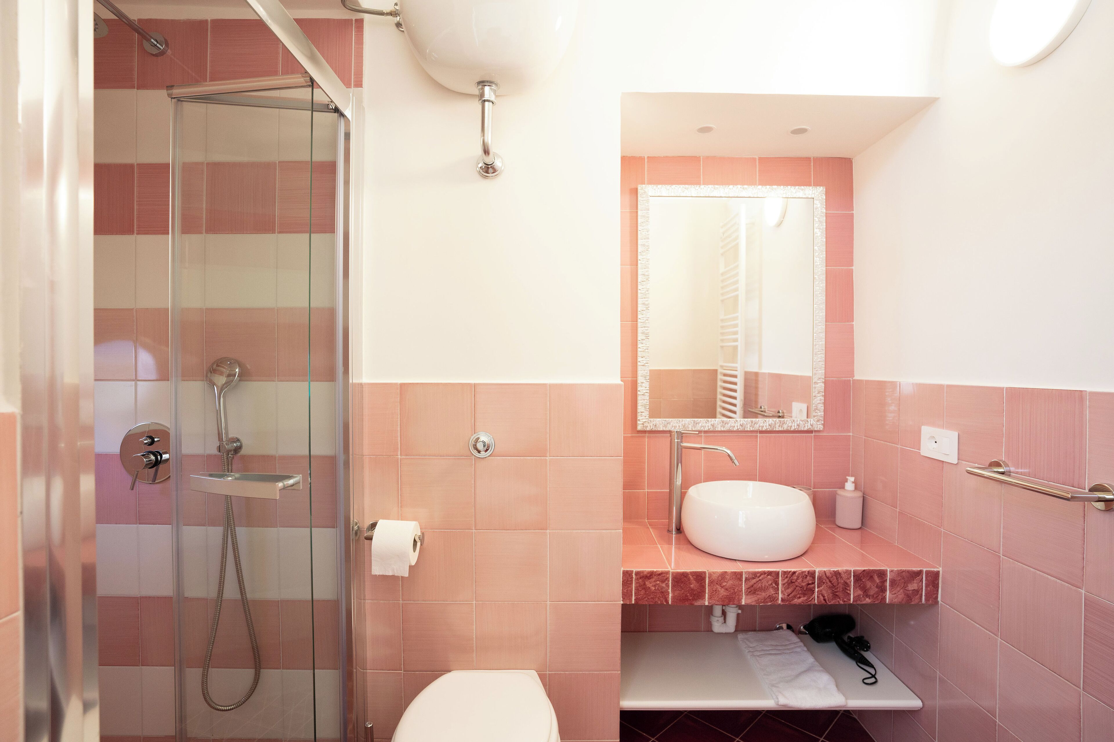 A bathroom with a glass-enclosed shower, a white sink, and a mirror above it.