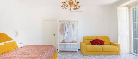 Une chambre à coucher avec un lit, un fauteuil jaune, une armoire et un lustre.