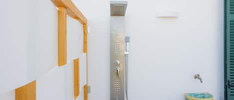 Un baño con ducha, lavamanos y una cesta decorativa.