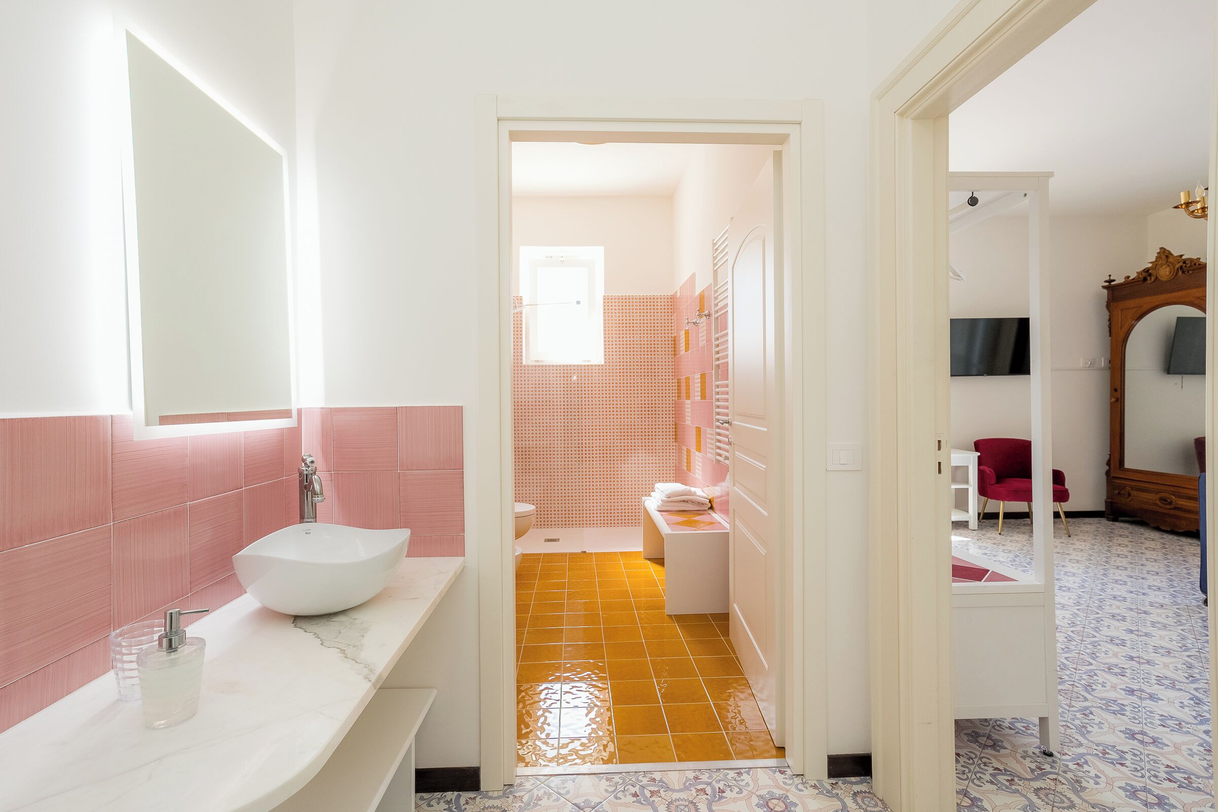 A bathroom with a white sink, pink tiles, and a patterned floor.