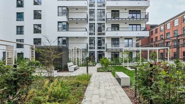 A modern apartment building with a central courtyard, outdoor seating, and a mix of balconies and windows. - Modern Apartment with Balcony | Parking, Close to the River (Gdansk)