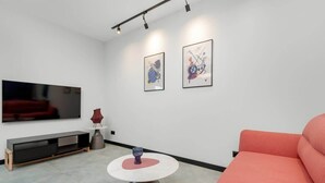 A modern living room with a flat-screen TV, a sofa, a coffee table, and two abstract paintings on the wall. - Modern Apartment with Balcony | Parking, Close to the River (Gdansk)