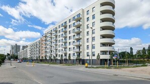 Ein modernes Mehrfamilienhaus mit mehreren Balkonen und einer gepflegten Stadtstraße.