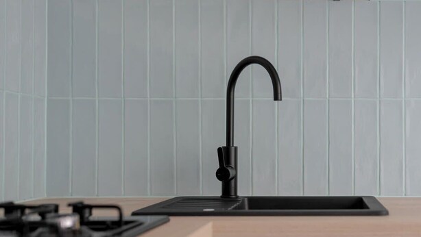 A modern kitchen with a black faucet, a sink, and a stove. - Traditional Apartment with Balcony | Close to the Park (Poznan)