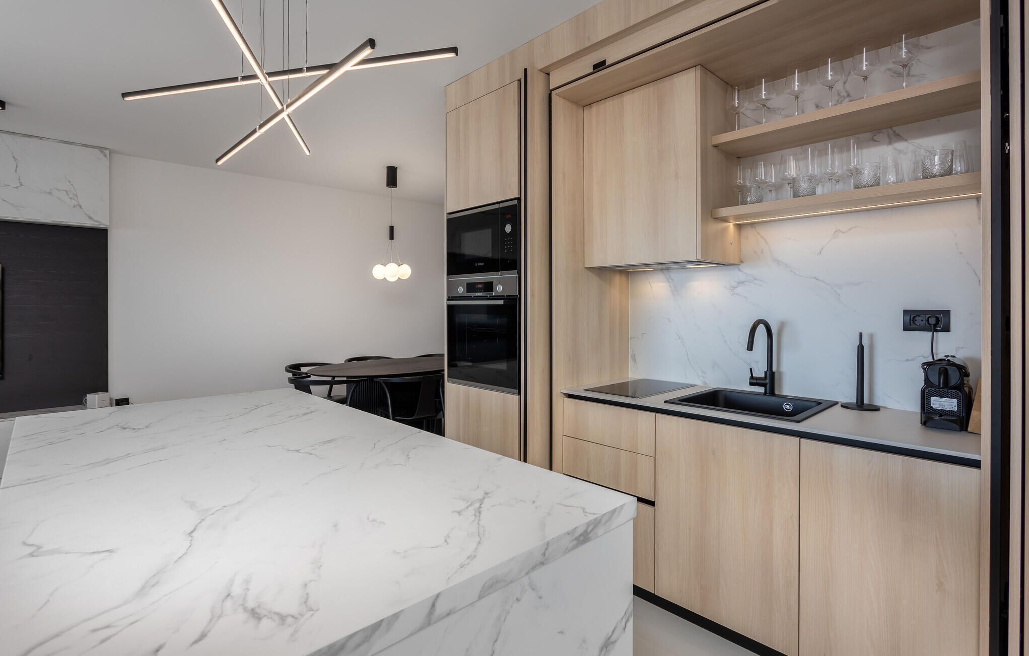 Une cuisine moderne dotée d’un plan de travail en marbre, de meubles en bois et d’un four encastré.