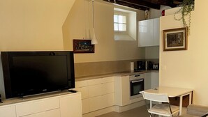 Une cuisine moderne avec des meubles blancs, une table à manger et un téléviseur.