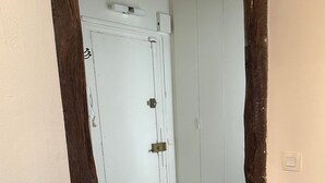 Un couloir avec une porte blanche, des poutres en bois et un interrupteur sur le mur.