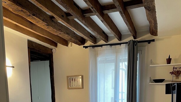 Un salon moderne avec un canapé, une petite table et un téléviseur. Il y a un balcon avec vue.