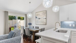 Una cucina moderna con mobili bianchi, una grande isola con lavello e un'area pranzo con tavolo e sedie.
