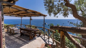An outdoor seating area with wooden furniture and a view of the sea.