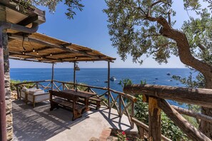 An outdoor seating area with wooden furniture and a view of the sea.